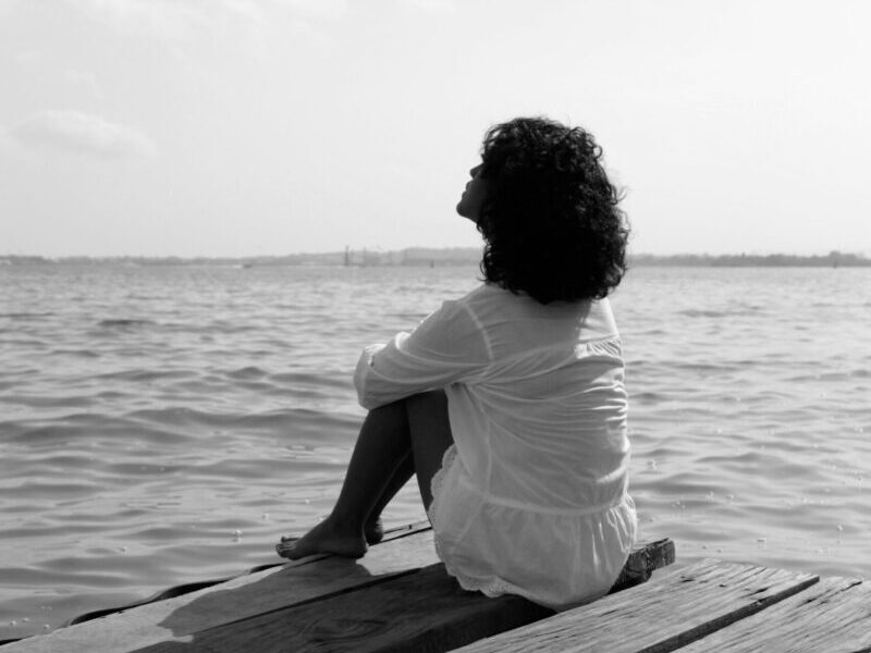 A woman sits peacefully on a pier, overlooking the sea in Cartagena, Colombia.